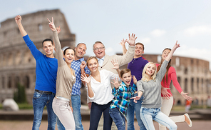 family, travel, tourism and people concept - group of happy men, women and boy having fun and waving hands over coliseum background