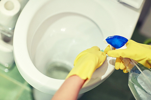 people, housework and housekeeping concept - close up of hand in rubber glove with detergent cleaning toilet pan