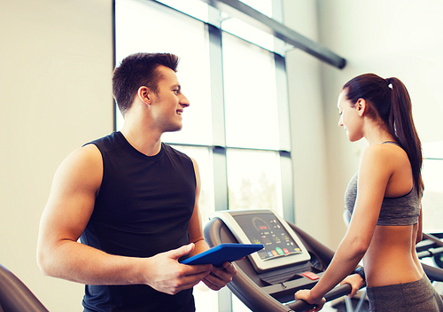 sport, fitness, lifestyle, technology and people concept - happy woman with trainer working out on treadmill in gym