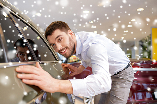 auto business, car sale, consumerism and people concept - happy man touching car in auto show or salon over snow effect