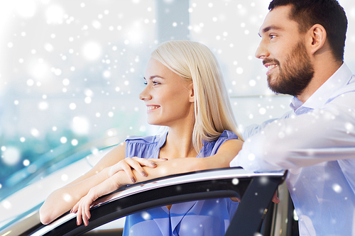 auto business, car sale, consumerism and people concept - happy couple buying car in auto show or salon over snow effect