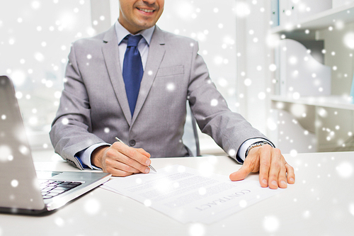 business, people, paperwork and technology concept - close up of smiling businessman with laptop computer and papers working in office over snow effect