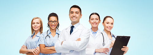 medicine, profession, teamwork and healthcare concept - international group of smiling medics or doctors with clipboard and stethoscopes over blue background