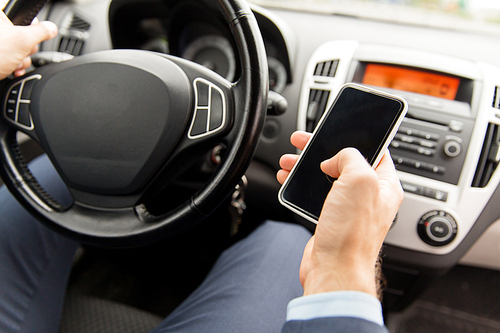 transport, business trip, technology and people concept - close up of young man hand with smartphone driving car