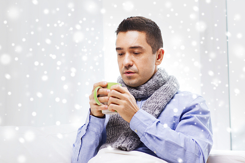 healthcare, people and medicine concept - ill man with flu drinking hot tea from cup at home over snow effect
