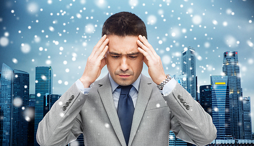 business, people, crisis and fail concept - businessman in suit having head ache over city background and snow