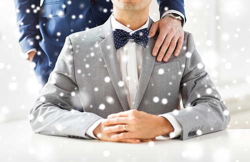 people, celebration, homosexuality, same-sex marriage and love concept - close up of male gay couple with wedding rings on putting hand on shoulder over snow effect