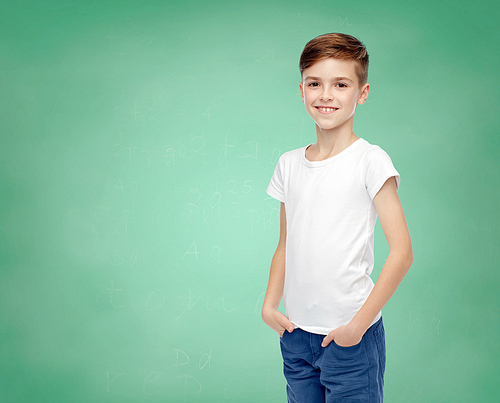 childhood, school, education, advertisement and people concept - happy boy in white t-shirt and jeans over green chalk board background