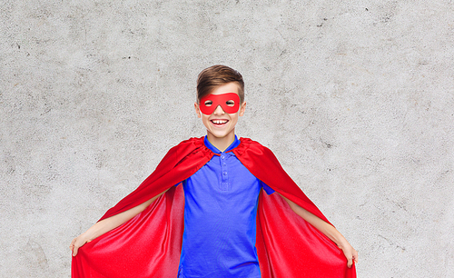 carnival, childhood, power and people concept - happy boy in red super hero cape and mask over gray background