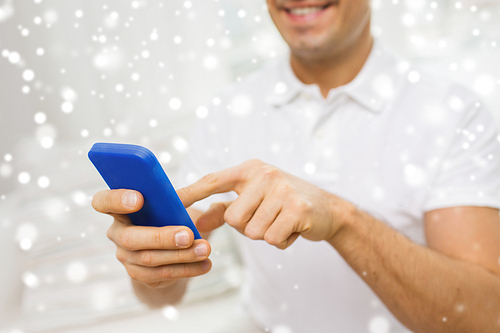 technology, people, lifestyle and communication concept - close up of happy man with smartphone at home over snow effect