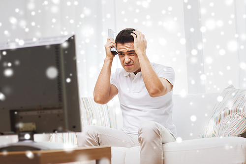 home, people, technology and entertainment concept - disappointed man watching sports on tv and supporting team at home over snow effect
