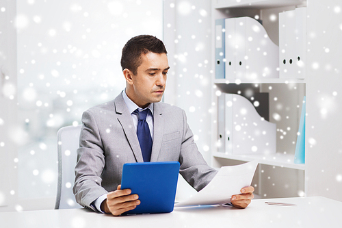 business, people, paperwork and technology concept - businessman with tablet pc and papers in office over snow effect