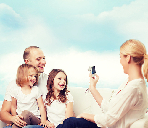 family, technology and people - smiling mother, father and little girls with camera over blue sky background