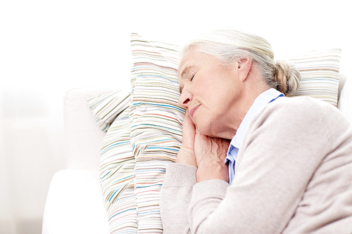 age, relax and people concept - happy senior woman sleeping on pillow at home