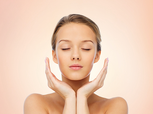 beauty, people, skincare and health concept - young woman face and hands over beige background