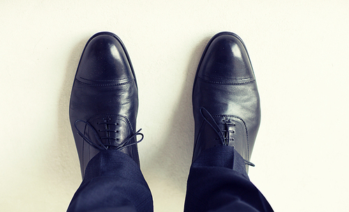 people, business, fashion and footwear concept - close up of man legs in elegant shoes with laces or lace boots