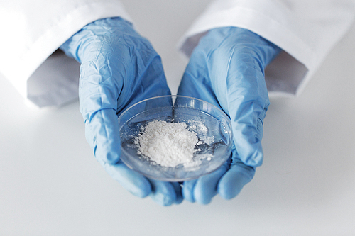 science, chemistry, biology, medicine and people concept - close up of scientist hands holding petri dish with powder in clinical laboratory