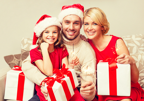 family, christmas, x-mas, happiness and people concept - smiling family in santa helper hats with many gift boxes and bengal lights