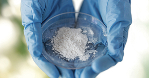 science, chemistry, biology, medicine and people concept - close up of scientist hands holding petri dish with powder over green background