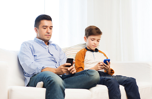 leisure, technology, technology, family and people concept - father and son with smartphones texting message or playing game at home