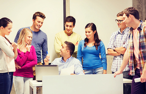 education, high school, technology and people concept - group of smiling students and teacher with papers, laptop computer in classroom