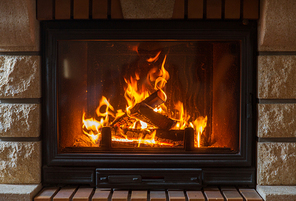 heating, warmth, fire and cosiness concept - close up of burning fireplace at home