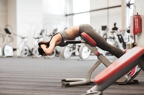 sport, training, fitness, lifestyle and people concept - young woman flexing back muscles on bench in gym