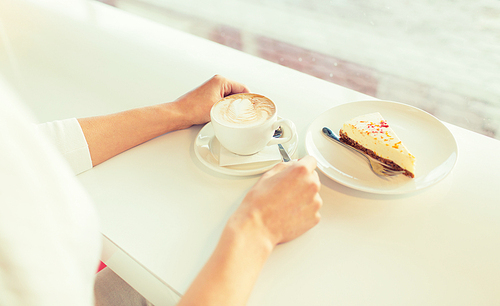 leisure, food and drinks, people and lifestyle concept - close up of young woman hands eating cake and drinking coffee at cafe