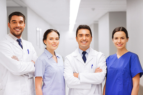 clinic, profession, people, health care and medicine concept - happy group of medics or doctors at hospital corridor