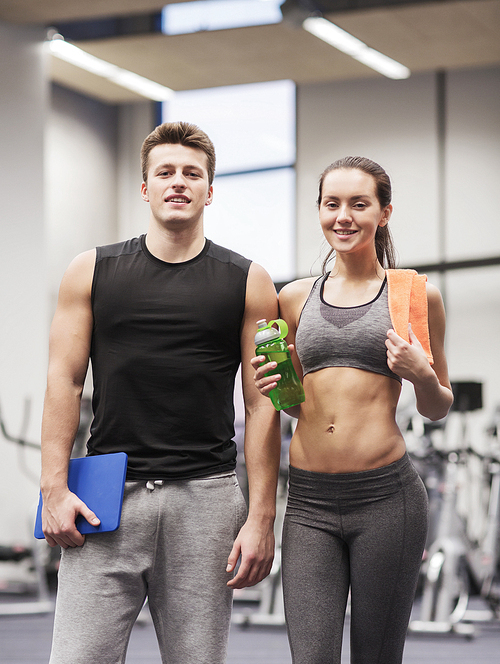fitness, sport, people and lifestyle concept - happy couple in gym with water, towel and tablet pc computer