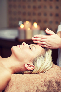 people, beauty, spa, healthy lifestyle and relaxation concept - close up of beautiful young woman lying with closed eyes and having face or head massage in spa