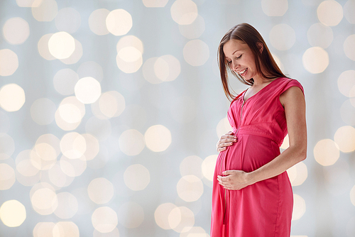 pregnancy, motherhood, people and expectation concept - happy pregnant woman with big tummy over holidays lights background