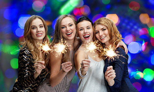 party, holidays, new year, nightlife and people concept - happy young women with sparklers over lights background