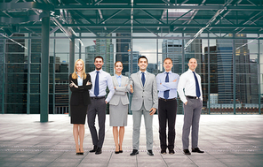 business, people, partnership and cooperation concept - group of smiling businesspeople over empty urban city construction background