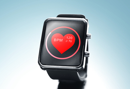 modern technology, object, health care and media concept - close up of black smart watch showing red heart beat icon on screen