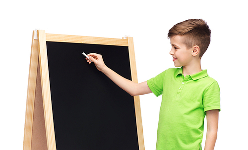 childhood, education, school, advertisement and people concept - happy smiling boy in green polo t-shirt with chalk and blank school blackboard