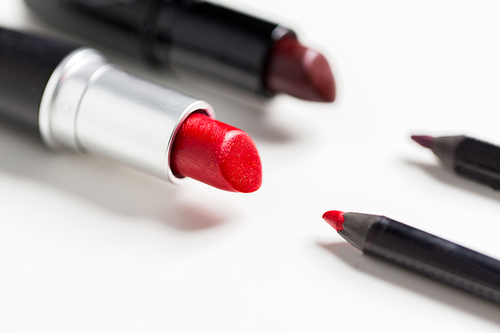 cosmetics, makeup and beauty concept - close up of two open lipsticks and lip pencils