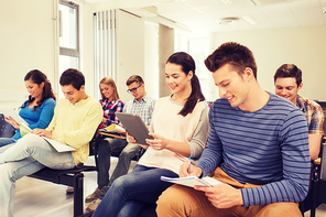 education, high school, teamwork and people concept - group of smiling students with tablet pc computers sitting in lecture hall