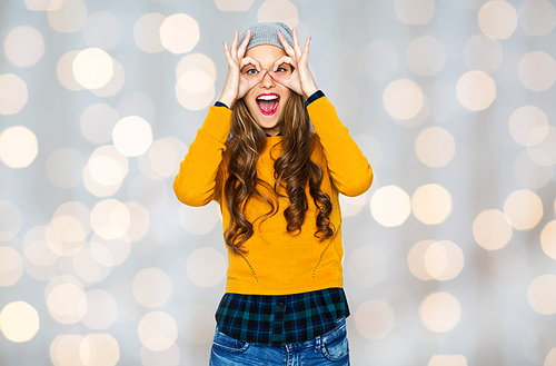 people, style and fashion concept - happy young woman or teen girl in casual clothes and hipster hat having fun over holidays lights background