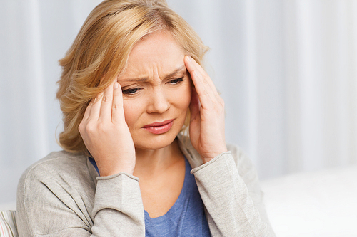 people, healthcare, stress and problem concept - unhappy woman suffering from headache at home