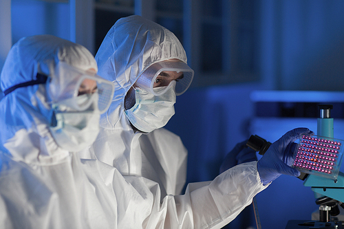 science, chemistry, medicine, research and people concept - close up of scientists looking at test sample plate in chemical laboratory