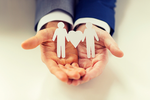 people, homosexuality, same-sex marriage and love concept - close up of happy male gay couple holding paper cutout love symbol