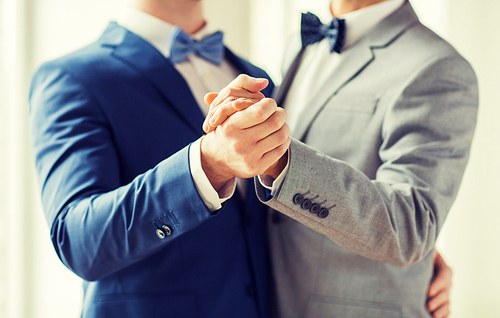 people, homosexuality, same-sex marriage and love concept - close up of happy male gay couple holding hands and dancing on wedding