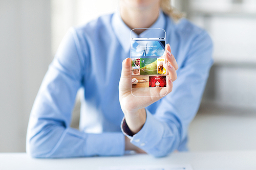 business, technology, mass media and people concept - close up of woman hand holding and showing showing news application on transparent smartphone screen at office