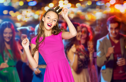 people, holidays, party, night life and fashion concept - happy young woman or teen girl in pink dress and princess crown dancing at disco club over crowd lights background