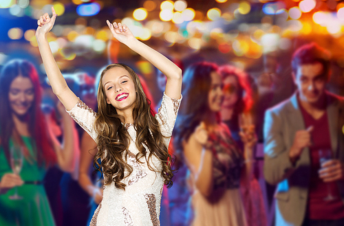 people, party, holidays, night life and entertainment concept - happy young woman or teen girl in fancy dress with sequins and long wavy hair dancing at disco club over crowd lights background