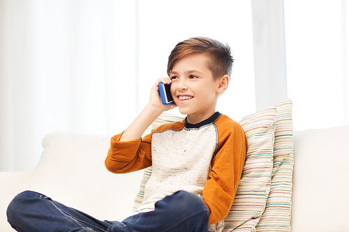 leisure, children, technology, communication and people concept - smiling boy calling on smartphone at home