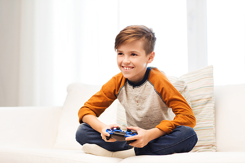 leisure, children, technology and people concept - smiling boy with joystick playing video game at home