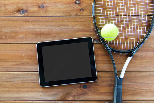 sport, fitness, technology, game and objects concept - close up of tennis racket with ball and tablet pc computer on wooden floor