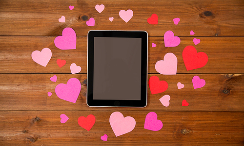 advertisement, romance, valentines day and holidays concept - close up of tablet pc computer and hearts on wood